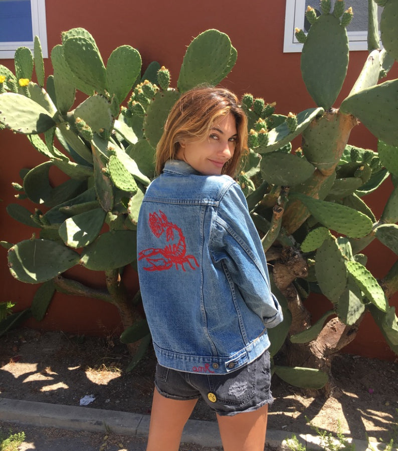 Woman wearing a custom denim jacket with red chainstitch embroidery by amR in Los Angeles