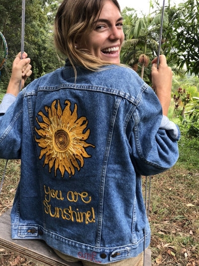 Bespoke denim jacket with hand-guided chainstitch sun artwork and custom back lettering