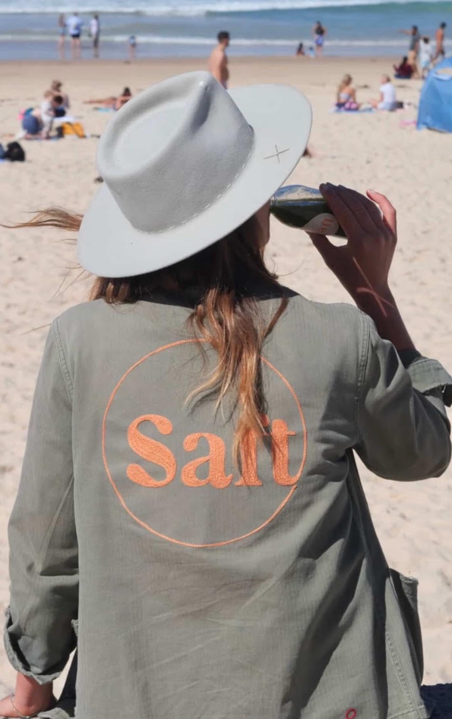 Custom chainstitch embroidered jacket with Salt lettering, worn on the beach in Sydney