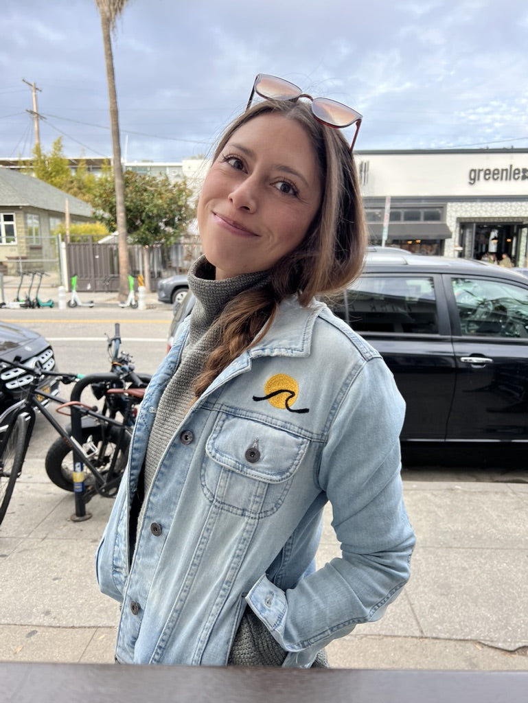 Woman wearing a light-wash denim jacket with custom chainstitch embroidery by amR in Los Angeles, California