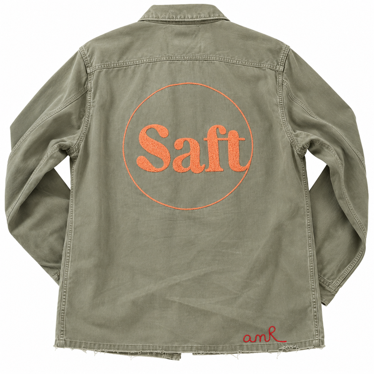 Custom chainstitch logo embroidery on an olive green overshirt, featuring large coral-orange Saft lettering with dense textured stitching inside a circular outline, a frayed hem and a red AMR signature on the back