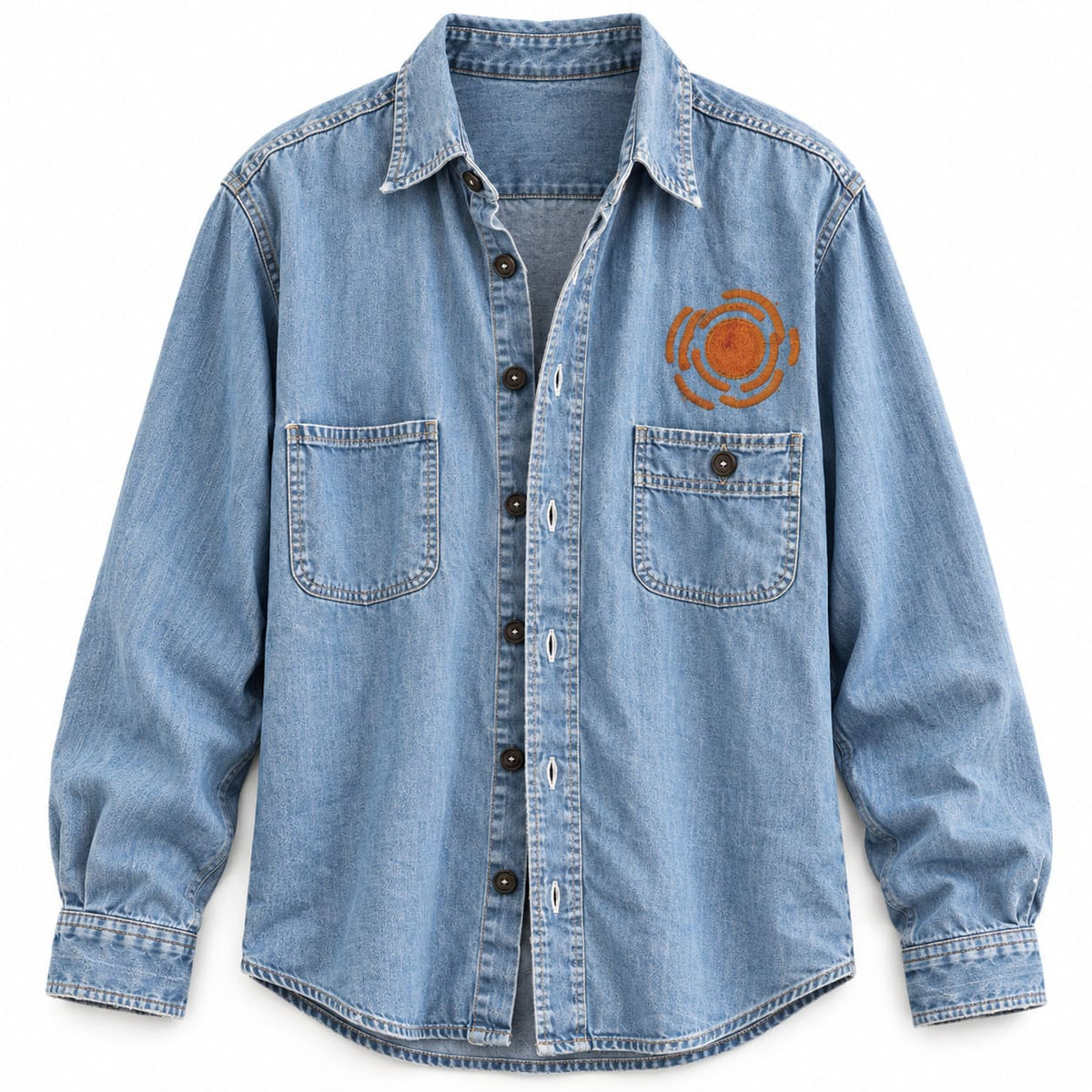 Bespoke chainstitch embroidery by amR on a light blue washed denim shirt, featuring a small burnt-orange sun-inspired logo with a textured circular center and curved stitched rays above the left chest pocket, custom made to order