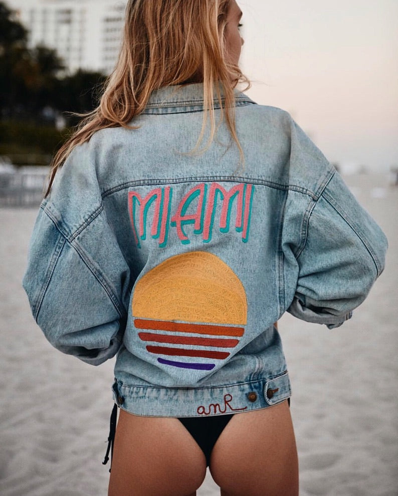 Woman wearing a custom embroidered denim jacket with colorful back embroidery