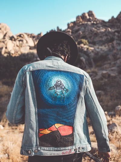 Custom embroidered denim jacket with astronaut artwork photographed in the Southern California desert