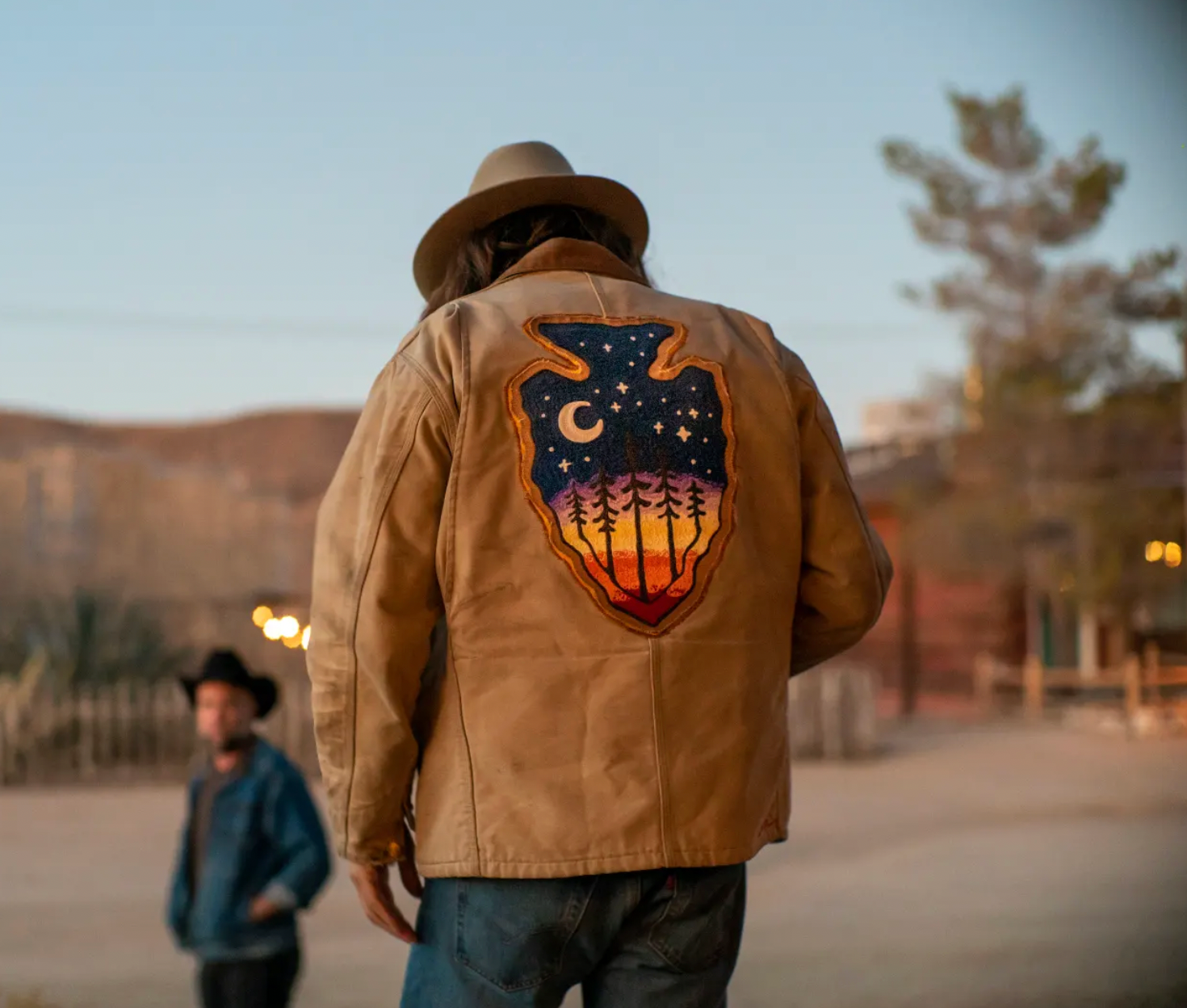 Custom embroidery on the back of a tan jacket with a colorful moon and forest design