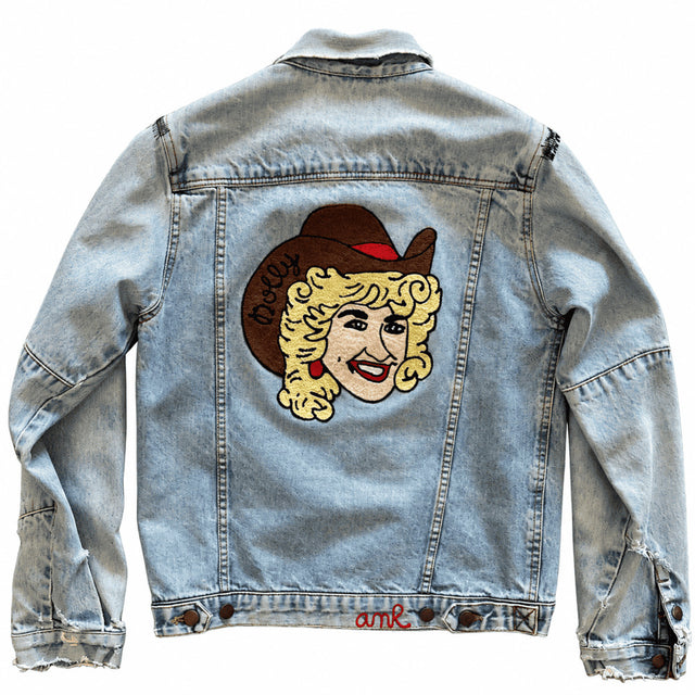 Custom chainstitch embroidered light-wash denim jacket by AMR featuring a detailed Dolly Parton back portrait with blonde curls, a brown cowboy hat, red accents and precise high-density stitching, showcasing premium bespoke embroidery craftsmanship
