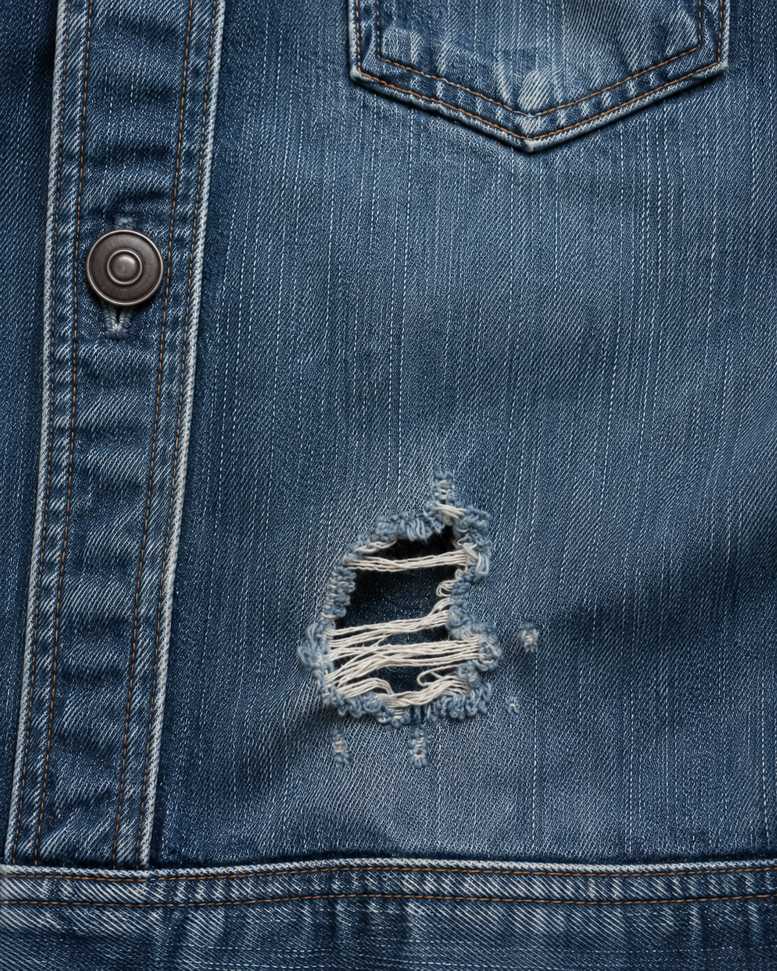 Worn blue denim jacket before repair, showing a tear and frayed fibers prior to professional denim darning in Los Angeles.