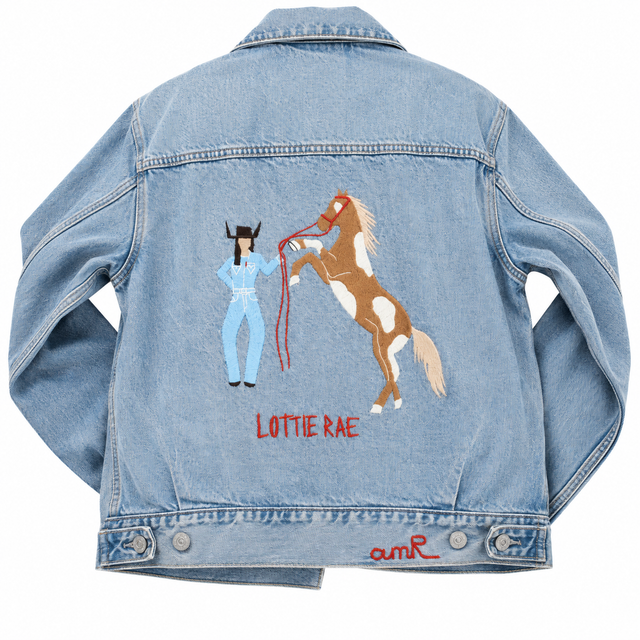 Custom chainstitch embroidery denim jacket created for Lottie Rae x Levi’s, featuring a cowgirl in a light blue western outfit beside a rearing brown and white horse, with LOTTIE RAE stitched in red on the back