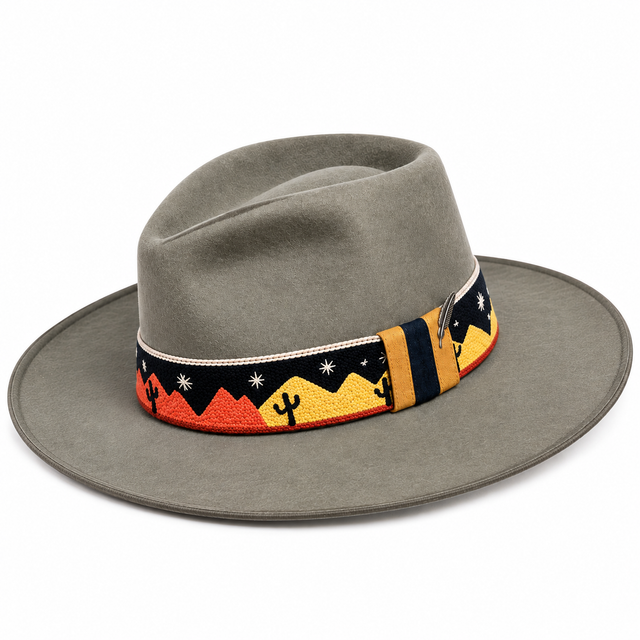 Bespoke chainstitch embroidery by amR for California hatmaker Wise Hatter, featuring a custom Southwestern desert hatband on a gray felt cowboy hat, with sunset-colored mountains, saguaro cacti, white stars, textured stitching, cream rope trim and a silver feather accent